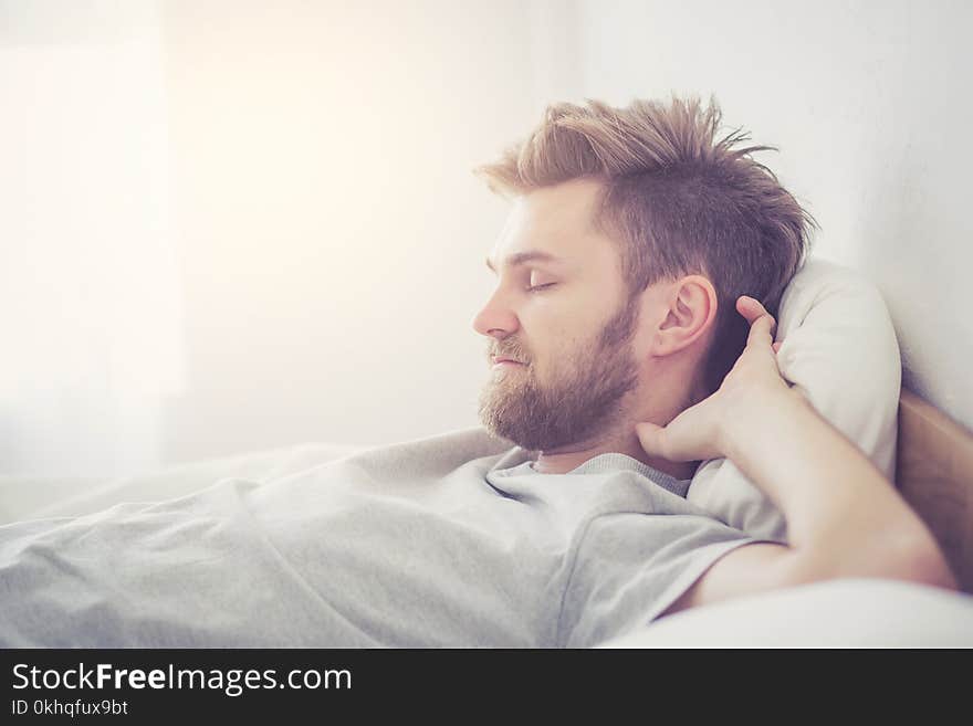 The handsome young american male sleeping in bed at home - healthcare concept.