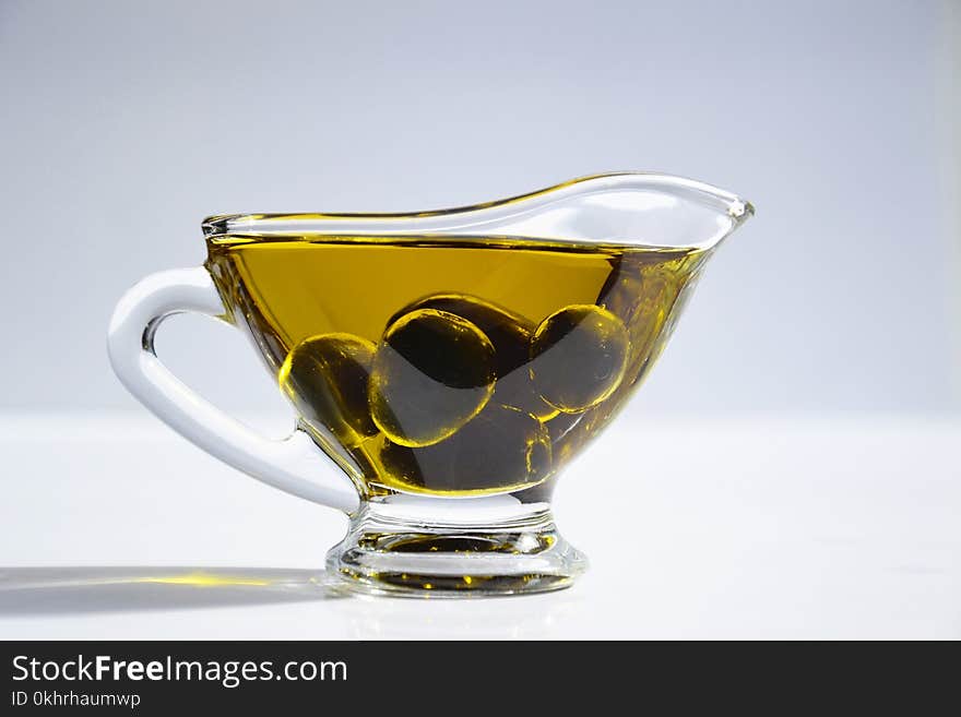 Photo of Olives on Cup of Olive Oil