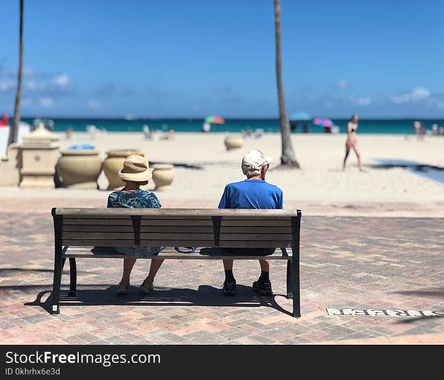 Man and Woman Sitting on Brown Wooden Bench