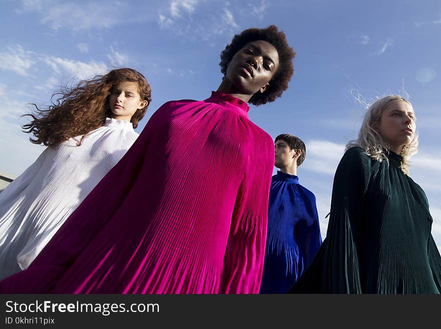 Low-angle Photography of Four Women in Assorted-color Long-sleeved Turtle-neck Dresses