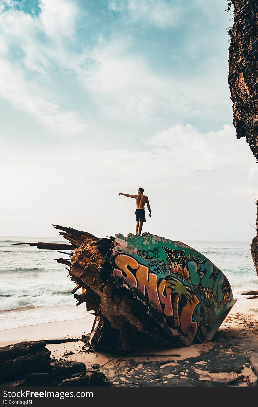 Photography of Man Standing on Destroyed Part of Ship