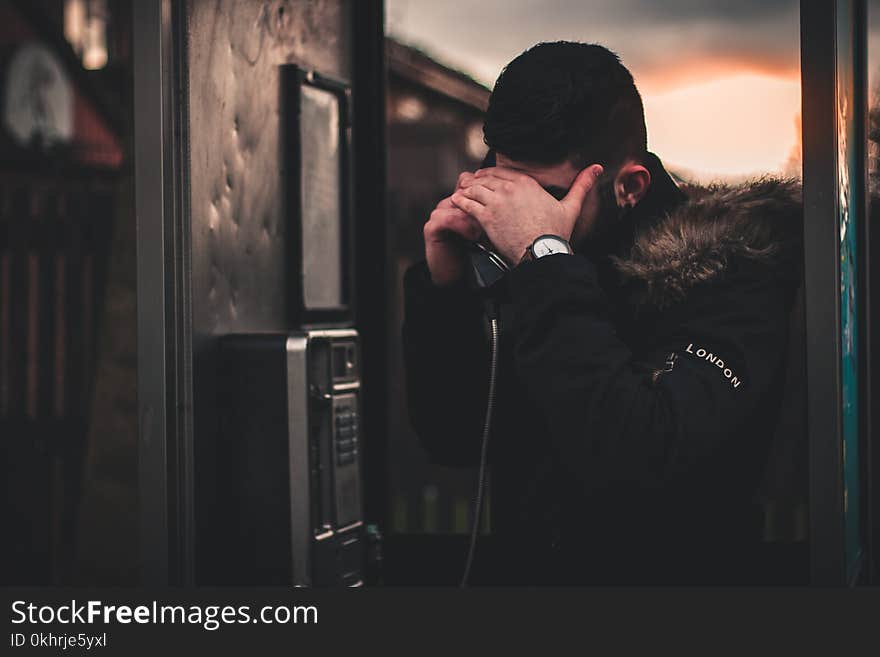 Man Wearing Black Parka Jacket Holding Telephone