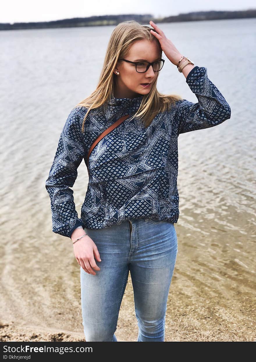 Woman in Blue and Gray Long-sleeved Shirt and Blue Denim Jeans Near Body of Water