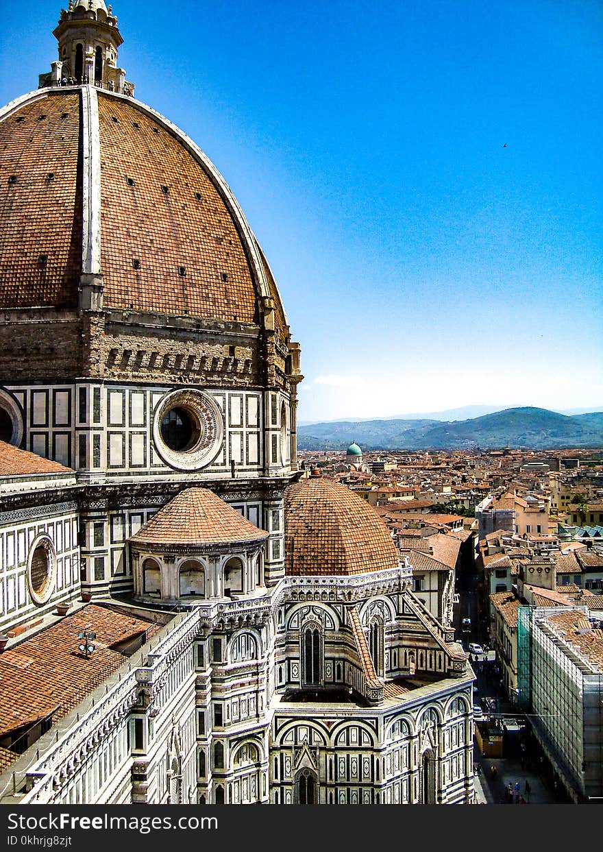 Brown and White Painted Cathedral Roof Overlooking City and Mountain Under Blue Sky