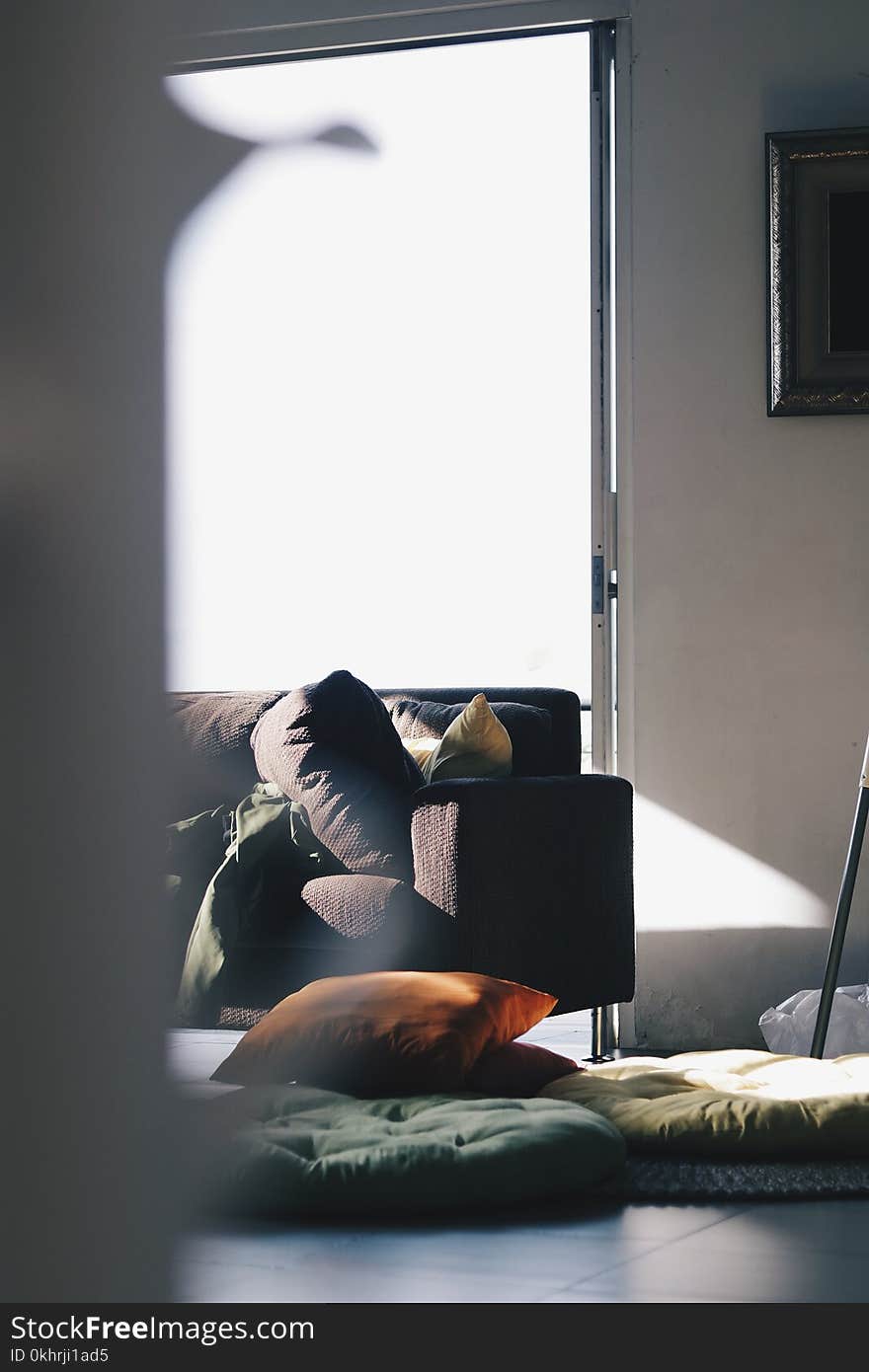 Brown Couch Near Pillows and Mats