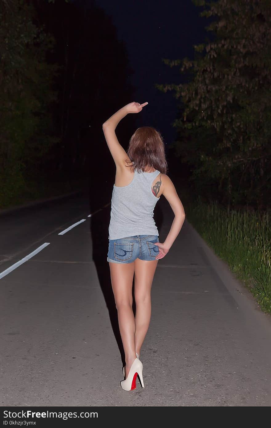 Girl showing obscene gestures at walking distance along road