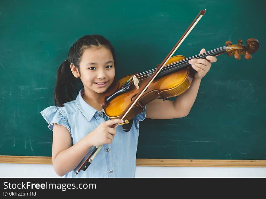 A littel cute girl playing violin on music class room at school. A littel cute girl playing violin on music class room at school