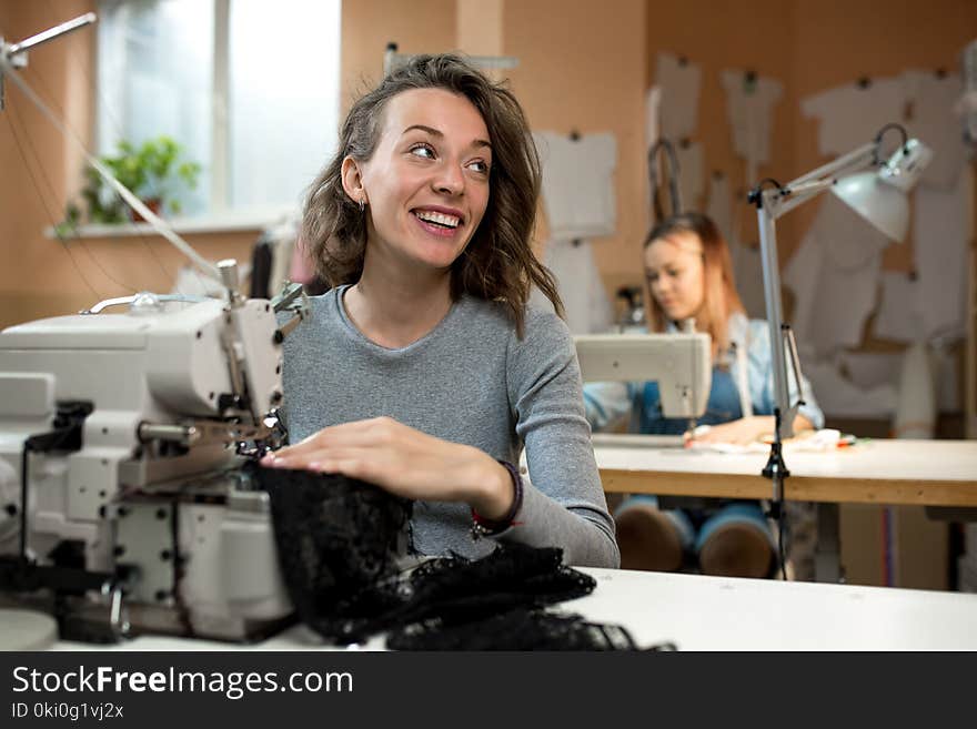 Two women dressmakers work in the workshop on sewing machines. Two women dressmakers work in the workshop on sewing machines