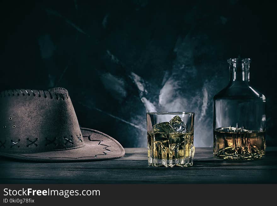 Glass of whiske and decanter with cowboy hat