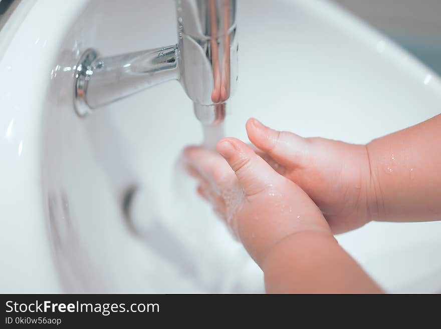 A boy is washing his hands himself.