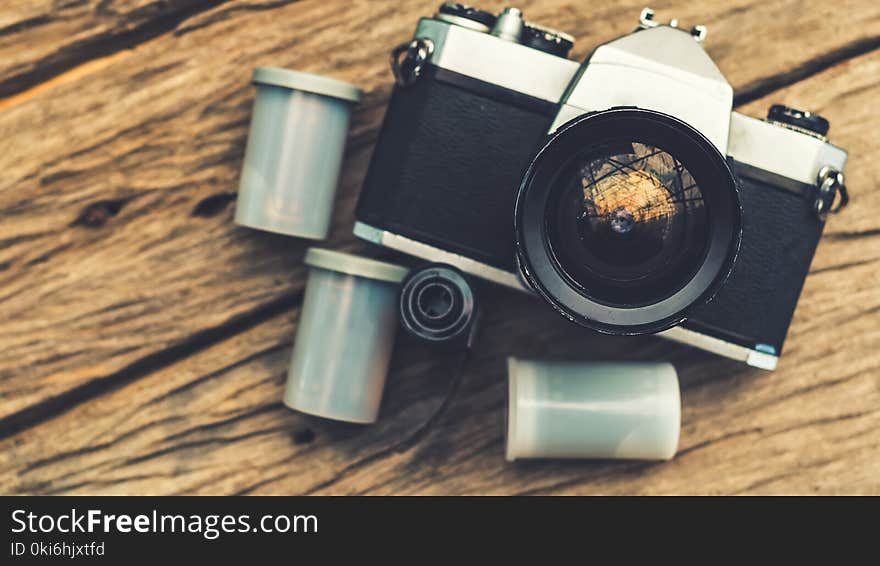 Old camera and film cassette on wooden board view from the top, retro color effect, select focus