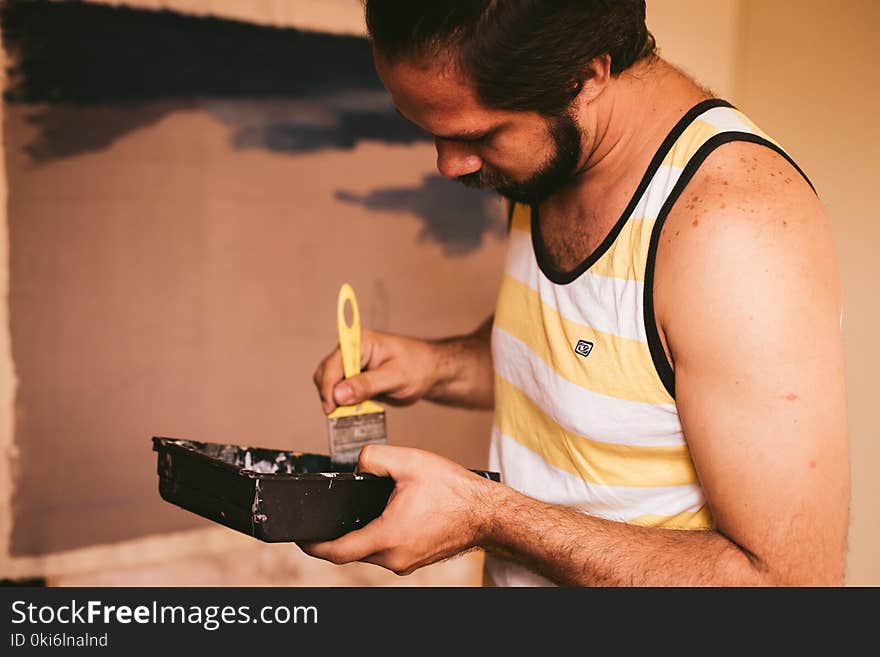 Man Holding Yellow Paint Brush