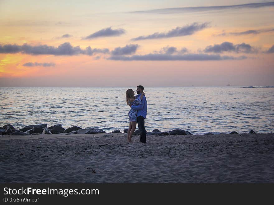 Couple Face to Face Stands on Seashore Near Calm Water during Golden Hour