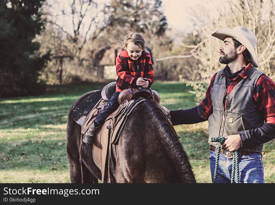 Little Girl Riding Horse Beside Man