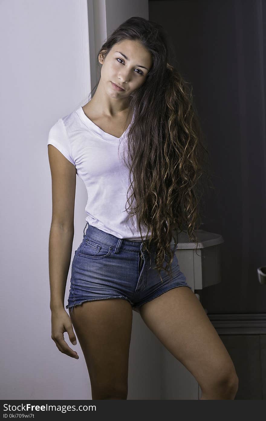 Young girl at home wearing a white t-shirt and blue shorts. Young girl at home wearing a white t-shirt and blue shorts