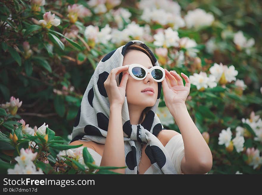 Redhead girl in white shawl near flowers