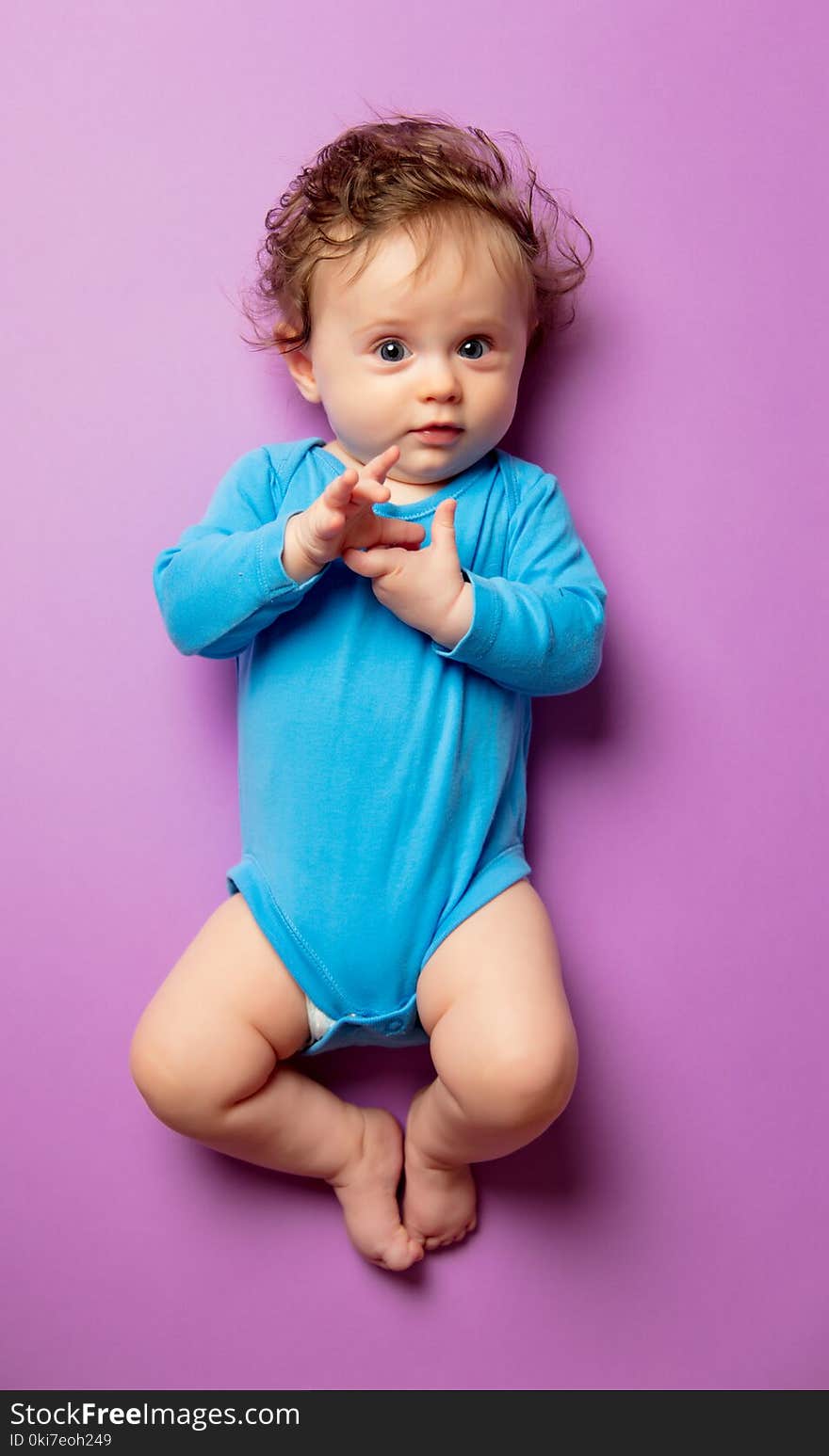 Little infant baby with hair lying down on purple background