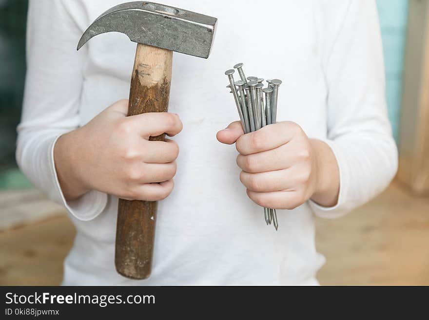 Child Holds A Hammer And Nails