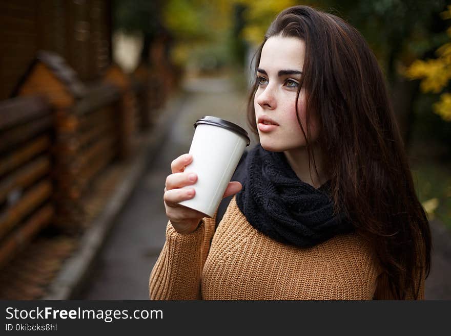 Young Woman Wearing Knitted Sweater Walking In The Autumn Park A