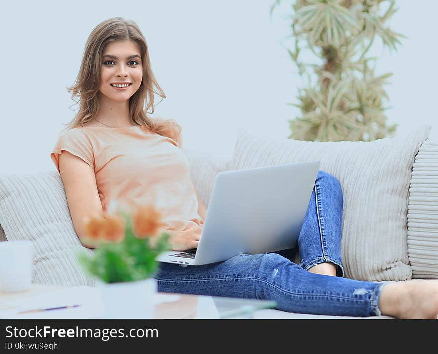 Beautiful girl with a laptop sitting on the couch. photo with copy space