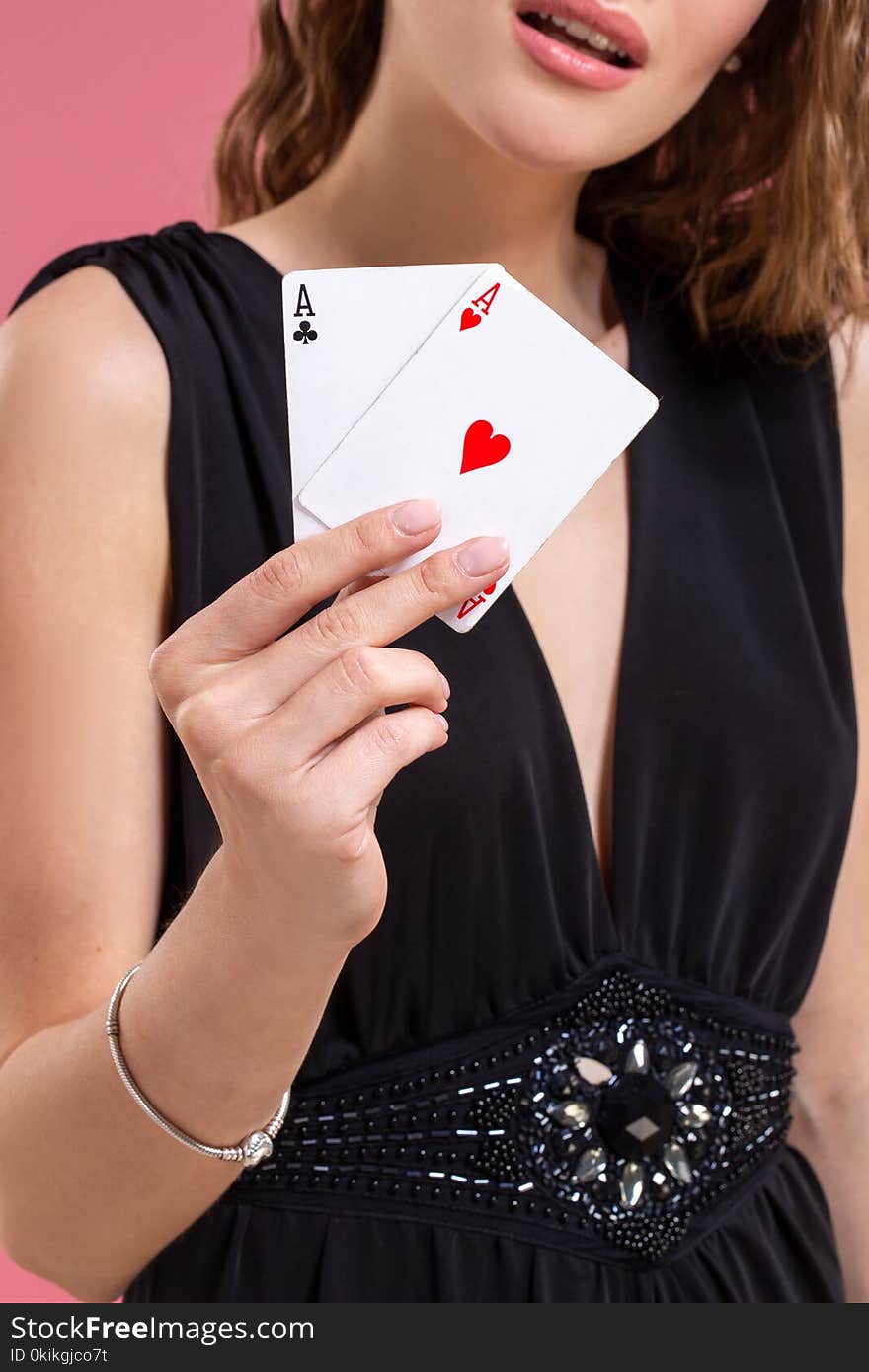 Beautiful caucasian woman in black dress with poker cards gambling in casino. Studio shot on a pink background. Beautiful caucasian woman in black dress with poker cards gambling in casino. Studio shot on a pink background