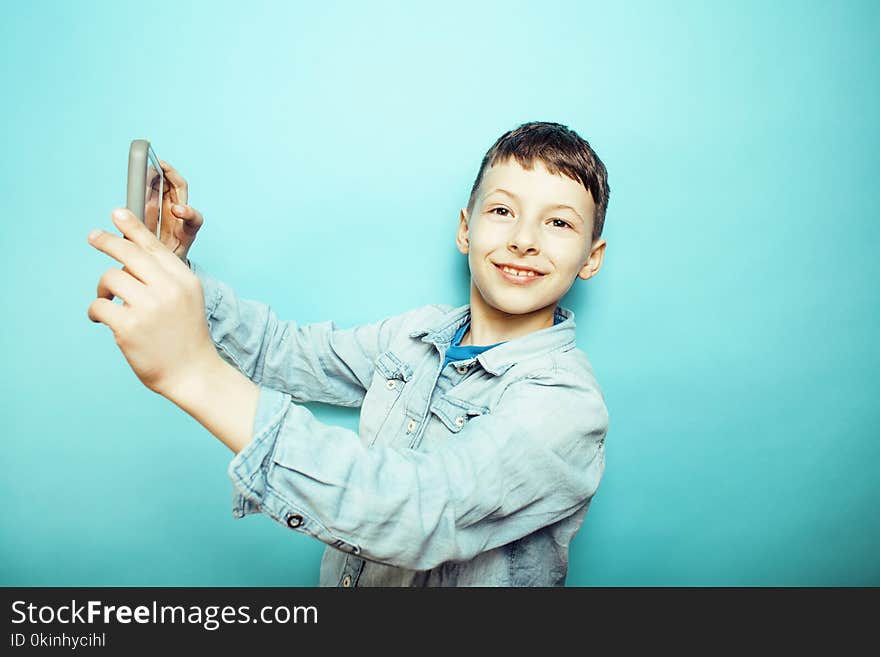 little cute boy posing emotional on blue background with smartph