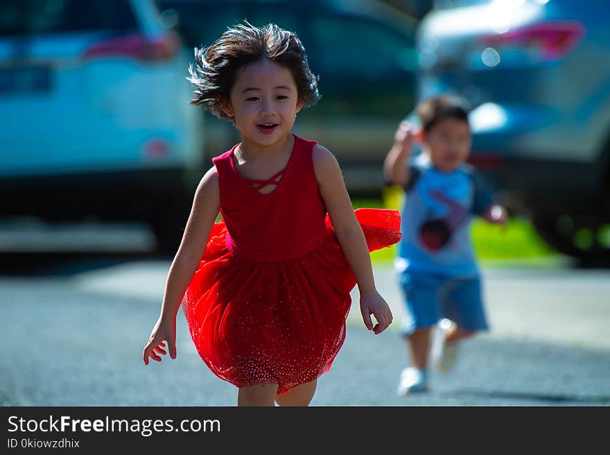 Photo of Girl in Red Dress Running on Street