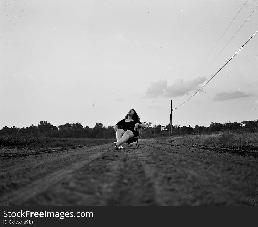 Grayscale Photography of Woman Sits on Chair on Pathway