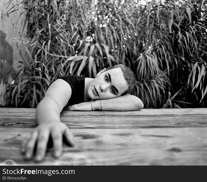 Grayscale Photo of a Person Leaning on Wooden Surface