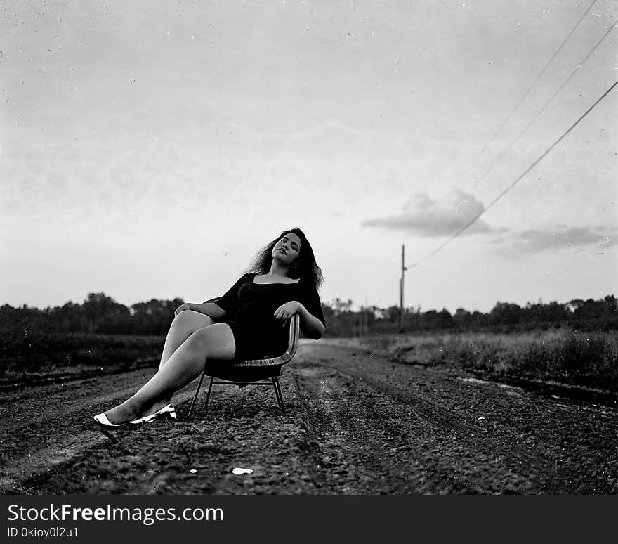 Black and White Photography of Woman on Chair on Road