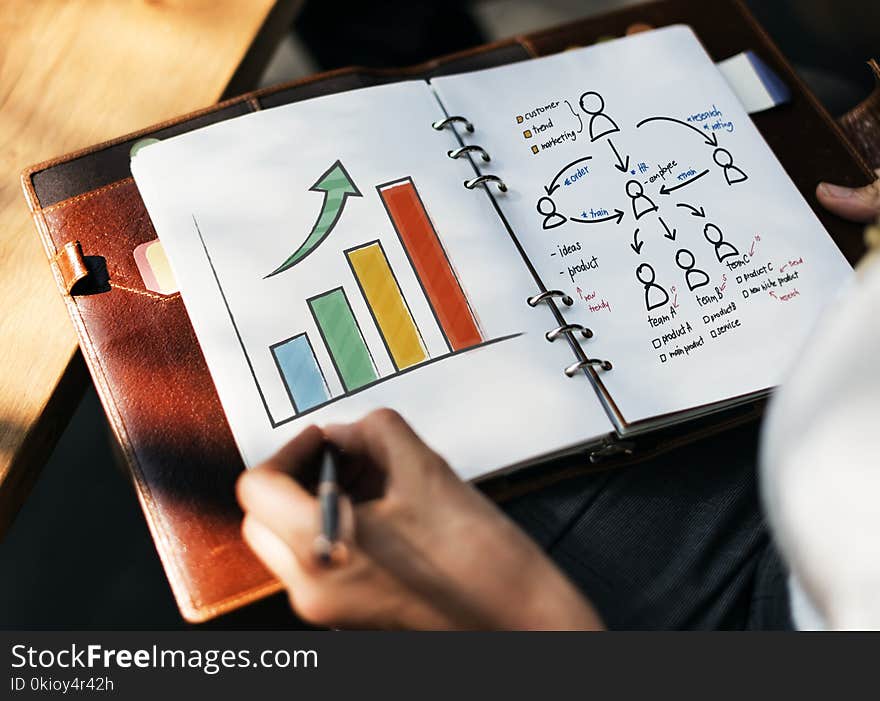 Person Holding Black Pen Writing on White Notebook