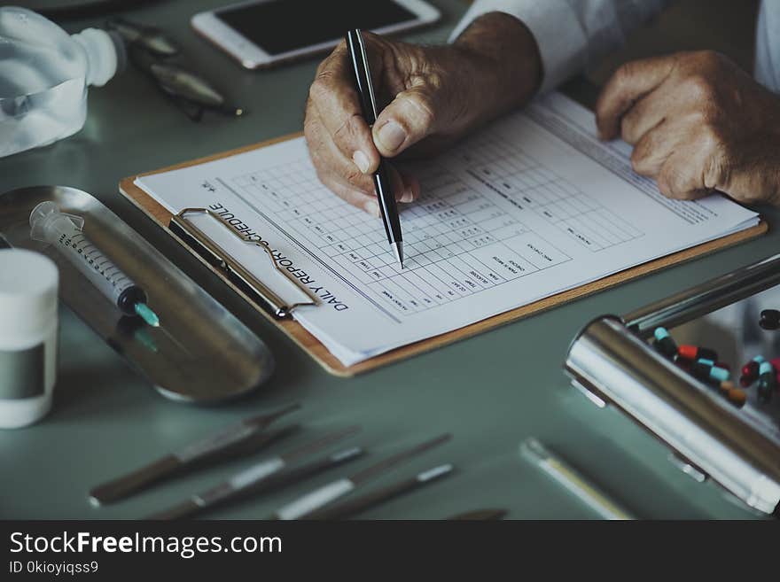 Person Holding Pen Writing on White Printing Paper