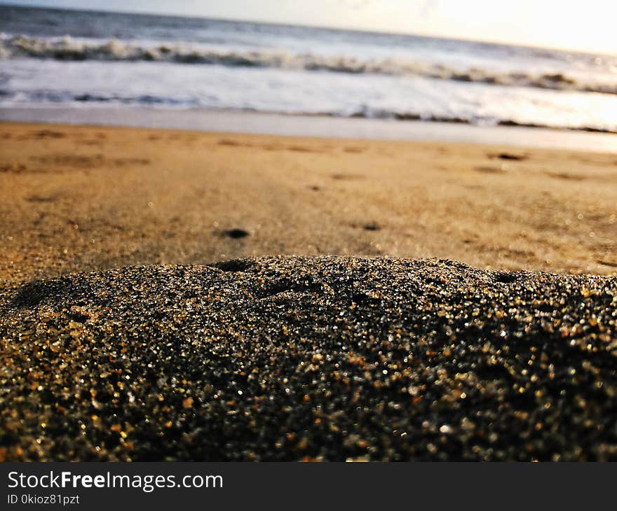 Low-angle Photography of Sand Near Body of Water