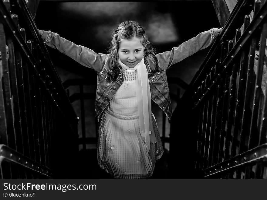 Grayscale Photo of Girl Standing on Stairs Holding Hand Rails