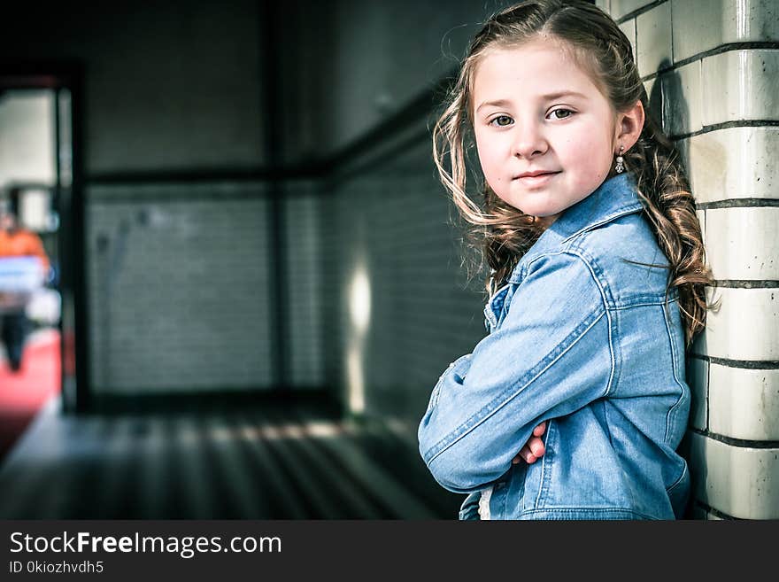 Girl in Blue Denim Jacket Leaning on Gray Wall