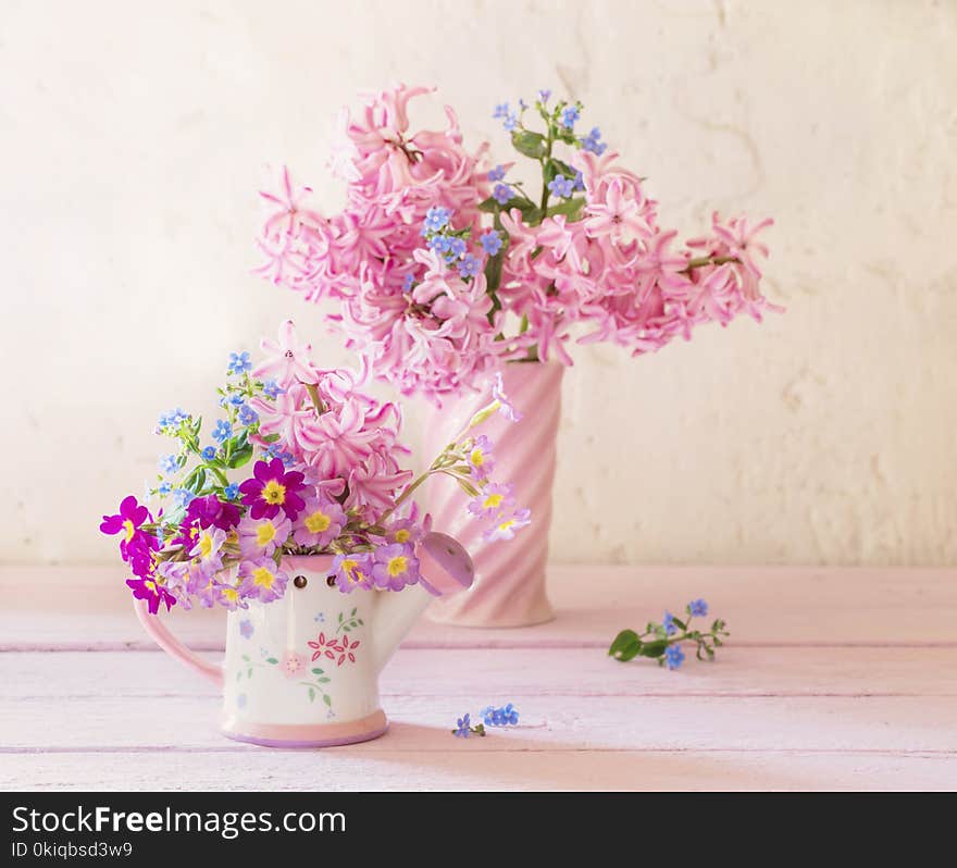 The spring flowers in vases on wooden table