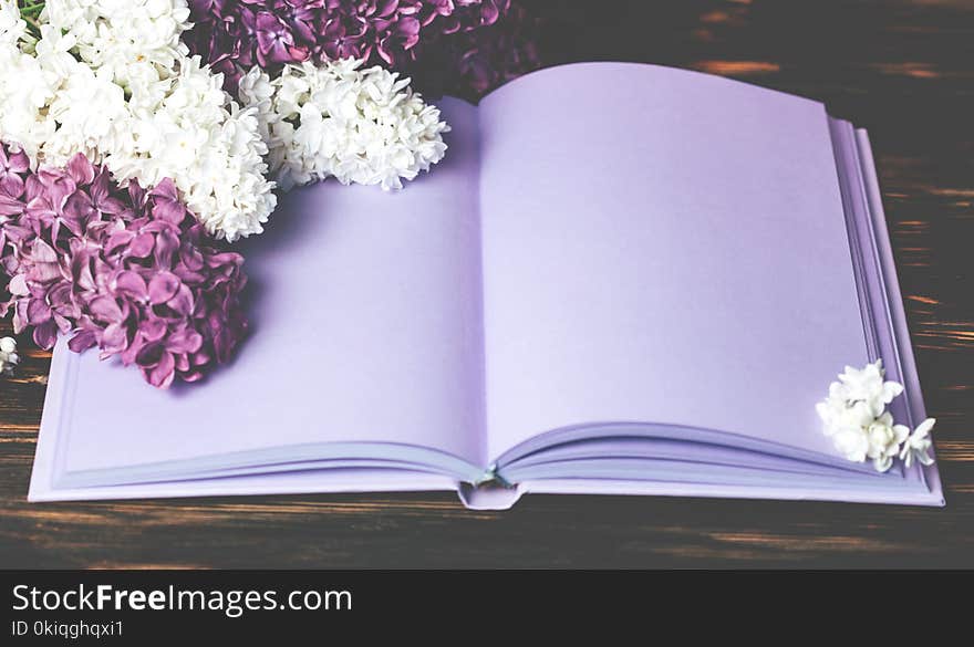 Mock up of Ultraviolet notebook and lilac flowers on brown wooden background. Mock up of Ultraviolet notebook and lilac flowers on brown wooden background