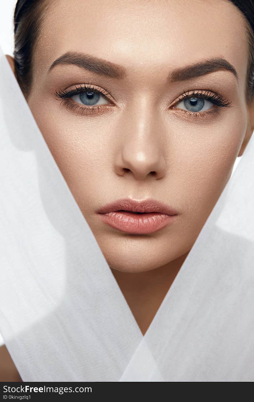 Face Skin Beauty. Beautiful Woman With Natural Makeup, Healthy Skin With White Pieces Of Fabric. High Resolution.