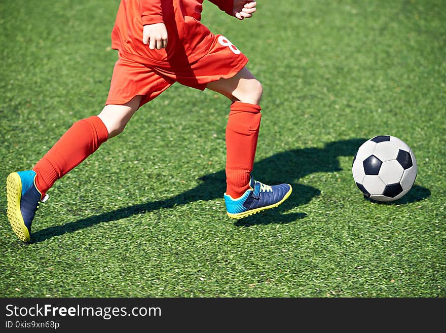 Child soccer player and ball on the football field