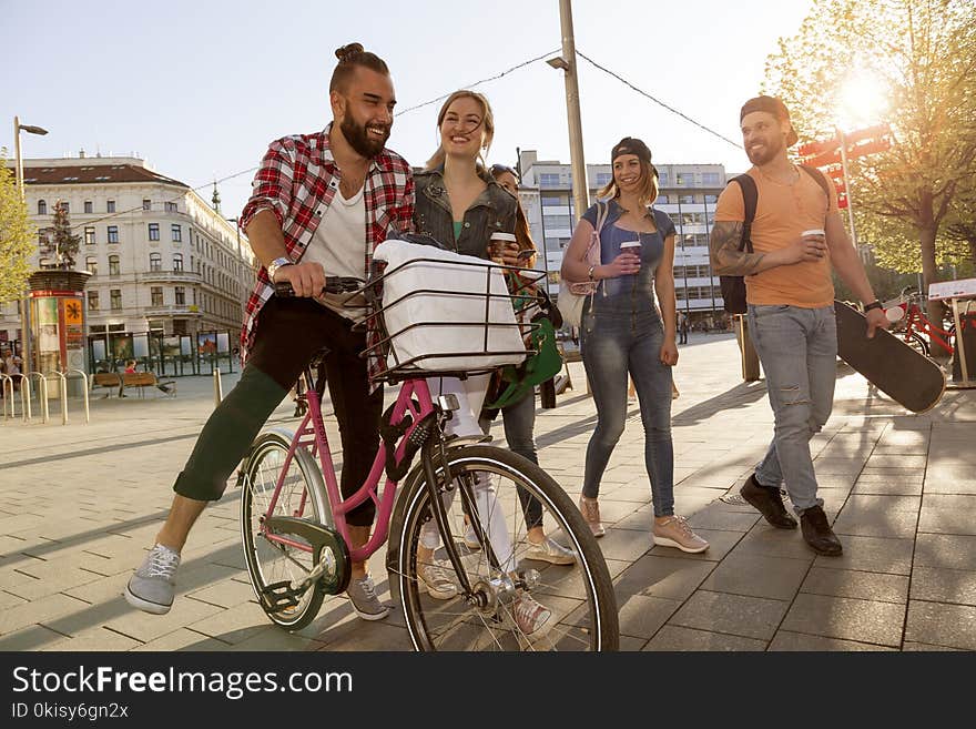 Best friends having fun in the city hanging with bike skateboard and coffee to go. sunlight back light from right with lens flares. capture from the side shot against the sunlight. Best friends having fun in the city hanging with bike skateboard and coffee to go. sunlight back light from right with lens flares. capture from the side shot against the sunlight.