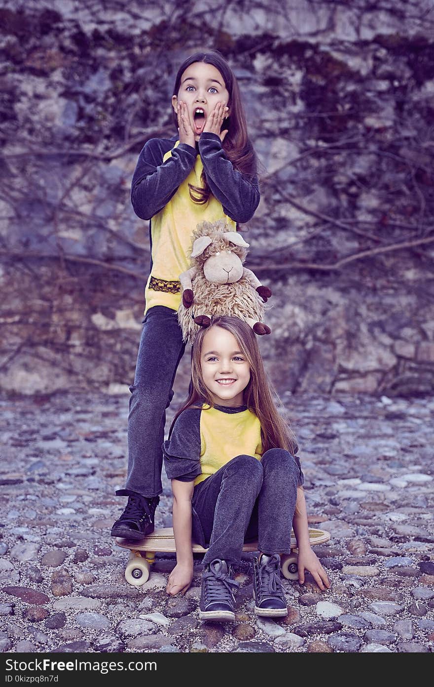 Two cute females teenager in yellow t shirt over rock background. Two cute females teenager in yellow t shirt over rock background.