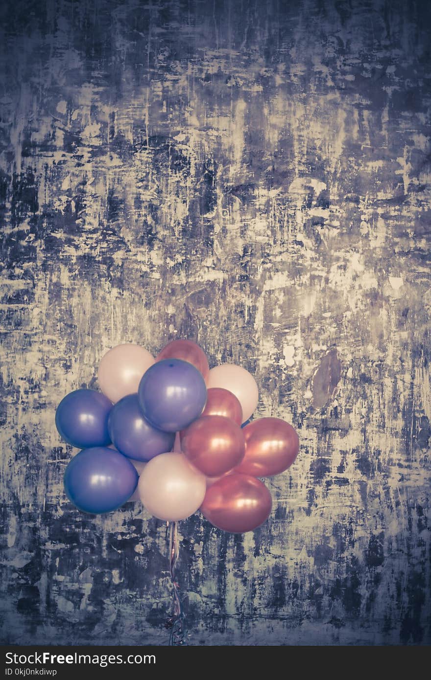 Bright balloons bunch against a textured wall