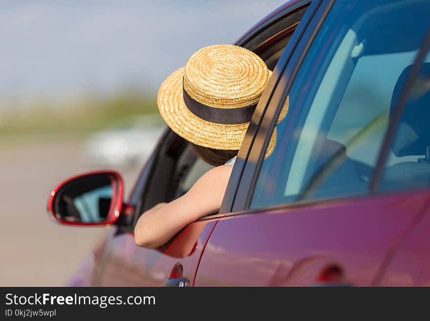 Young woman in car. Girl driving a car. Smiling young woman sitting in red car