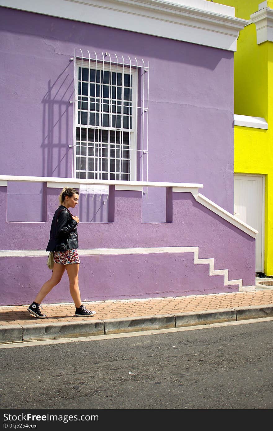 Woman Walking Near Purple Painted Building