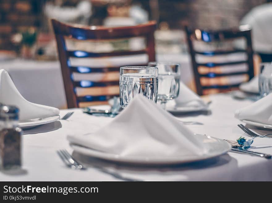 Depth of Field Photo of Clear Drinking Glass on White Table Near Plate