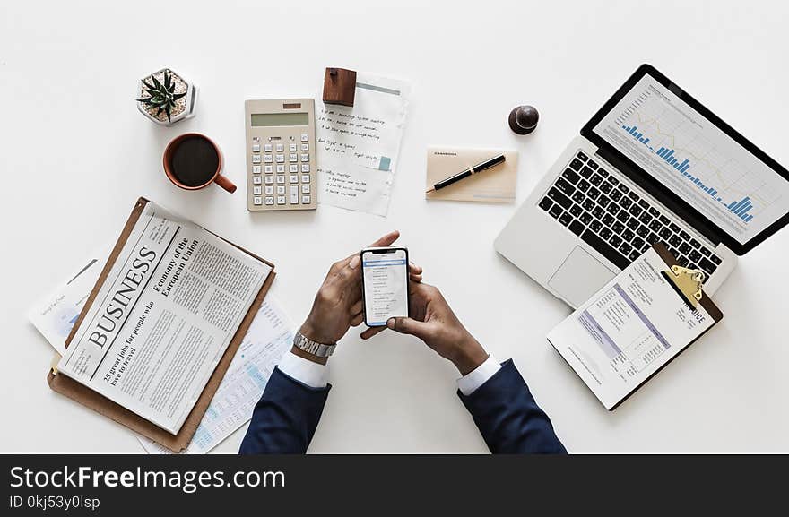 Top View of Man Holding Android Smartphone Near Macbook and Newspaper