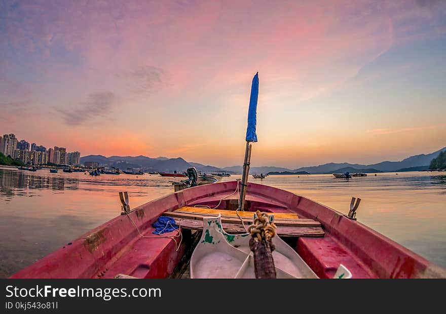 Red Boat on Body of Water With Blue Flag