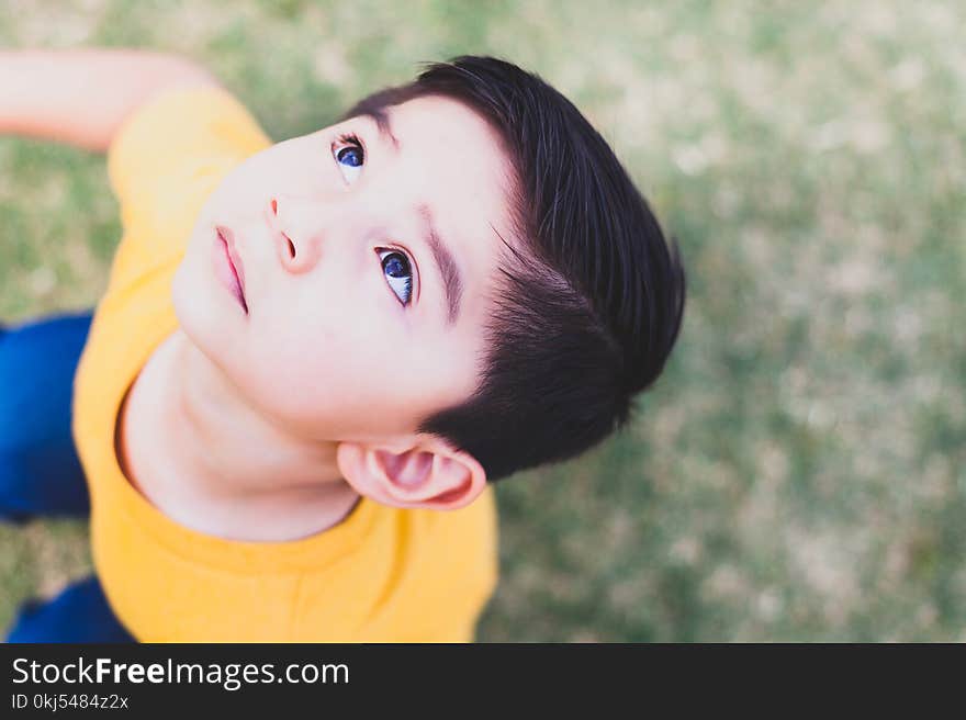 Boy Wearing Yellow Crew-neck T-shirt and Blue Bottoms Outfit Looking Above