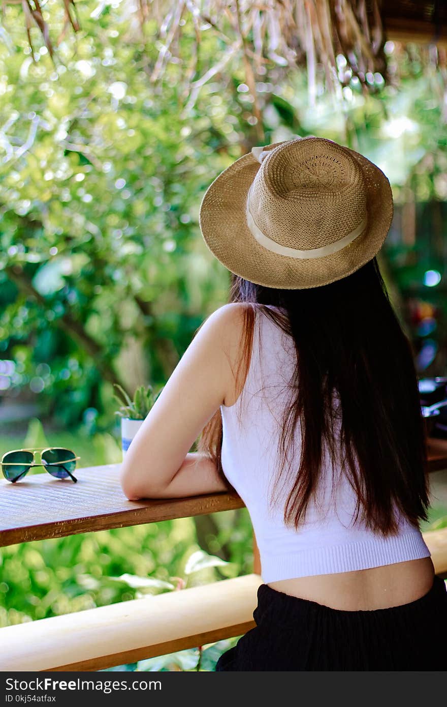 Woman Wearing White Tank Top and Black Pants With Brown Sun Hat