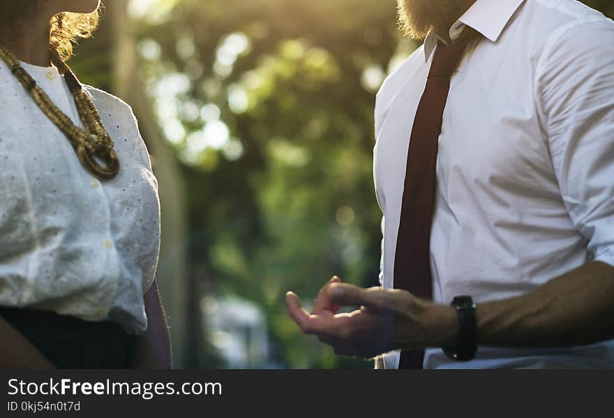 Man Wearing White Shirt Holding Out Hand in Front of Woman in White Lace Top